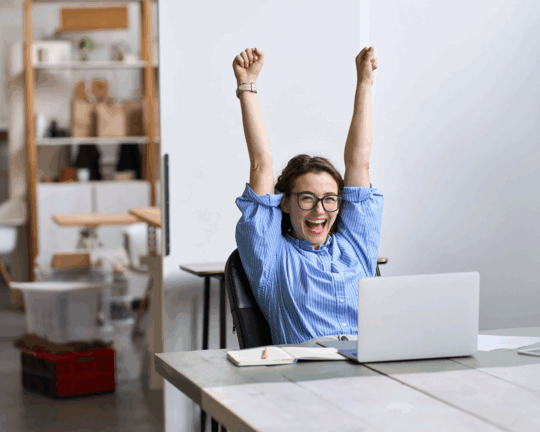 woman happy at desk with arms up