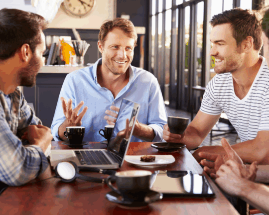 men sitting around a table with coffee and laptop